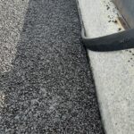 Czarny grys na płaskim dachu przy betonowym murku i metalowej krawędzi