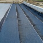 Hydroizolacja na betonowym moście w budowie, z wiejską drogą i polami w tle