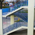 Wielopoziomowe schody i podjazdy dla pieszych z niebieskimi barierkami przy ulicy