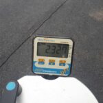 Cyfrowy wskaźnik siły AEP Transducers DFI pokazujący wartość 2.327 na tle asfaltu