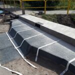 Remont schodów i chodnika przy kanale, z nowym betonowym murkiem i żółtą barierką