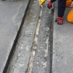 Robotnicy naprawiają szczelinę w nawierzchni drogi
