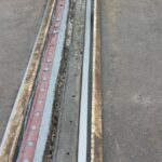 Pracownik w pomarańczowym stroju montuje szczelinę dylatacyjną w betonowej nawierzchni